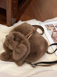 Brown fur bag with a leather strap on a wooden floor