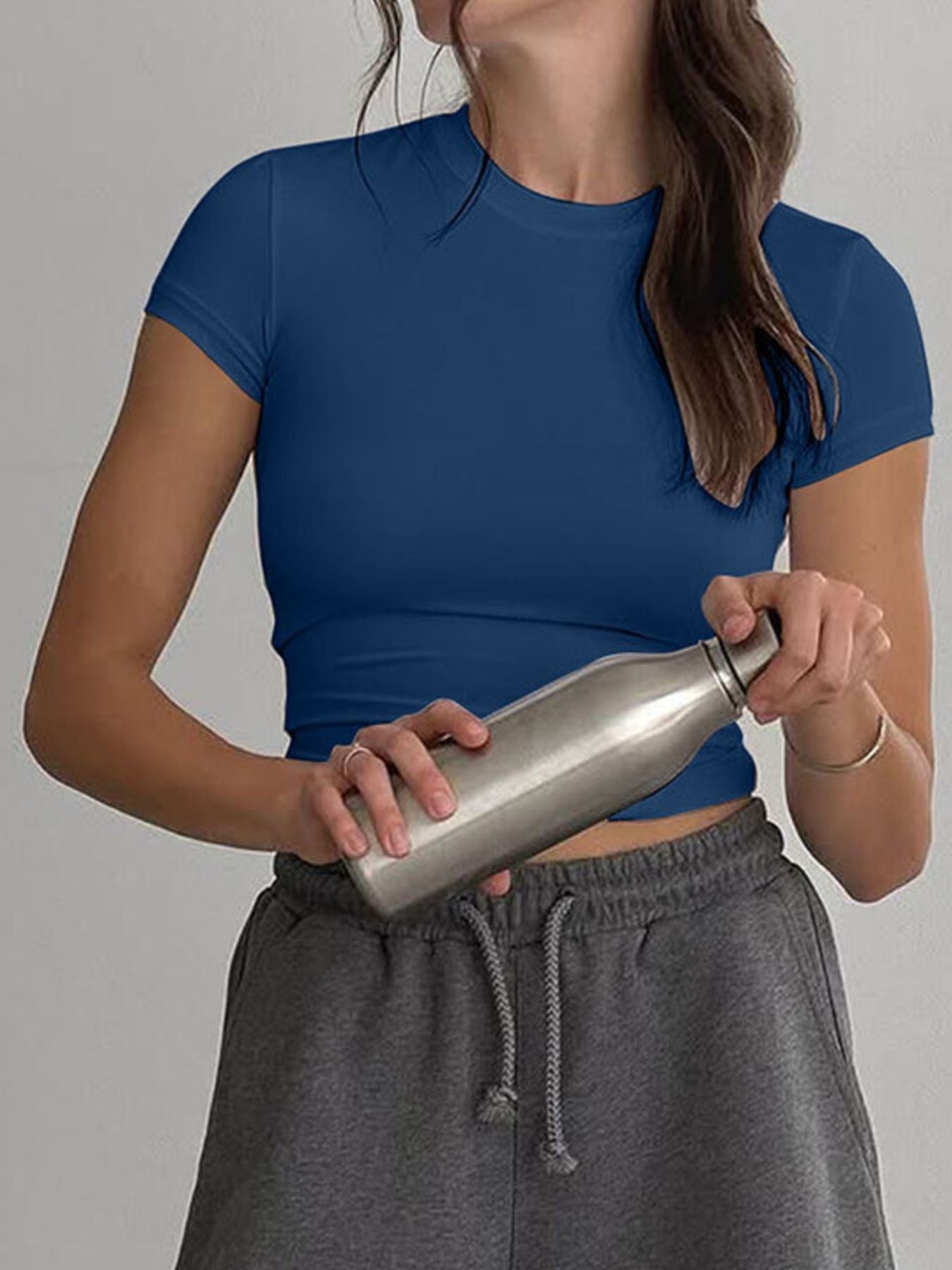 Person holding a silver water bottle against a gray background