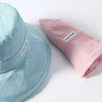 Light blue and pink bucket hats with 'Cacau&Co' branding on a white background