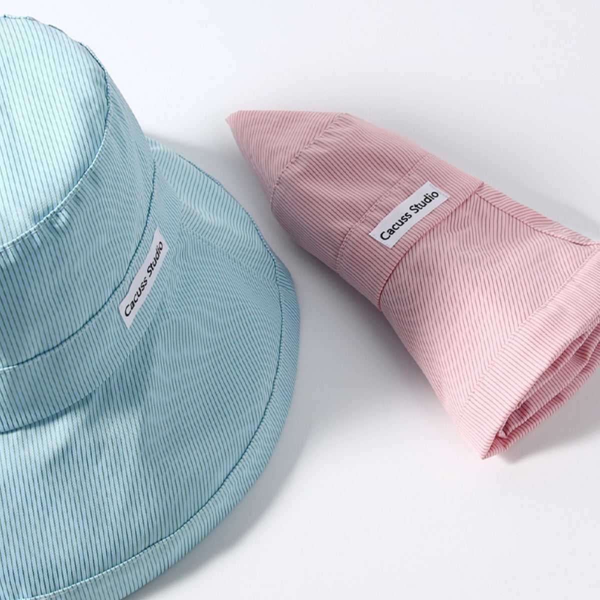 Light blue and pink bucket hats with 'Cacau&Co' branding on a white background