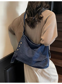 Person wearing a blue denim bag with button details on a neutral background