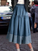 Person wearing a blue denim skirt on a street.