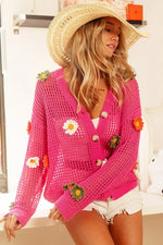 Woman wearing a pink crochet cardigan with floral decorations in a kitchen setting