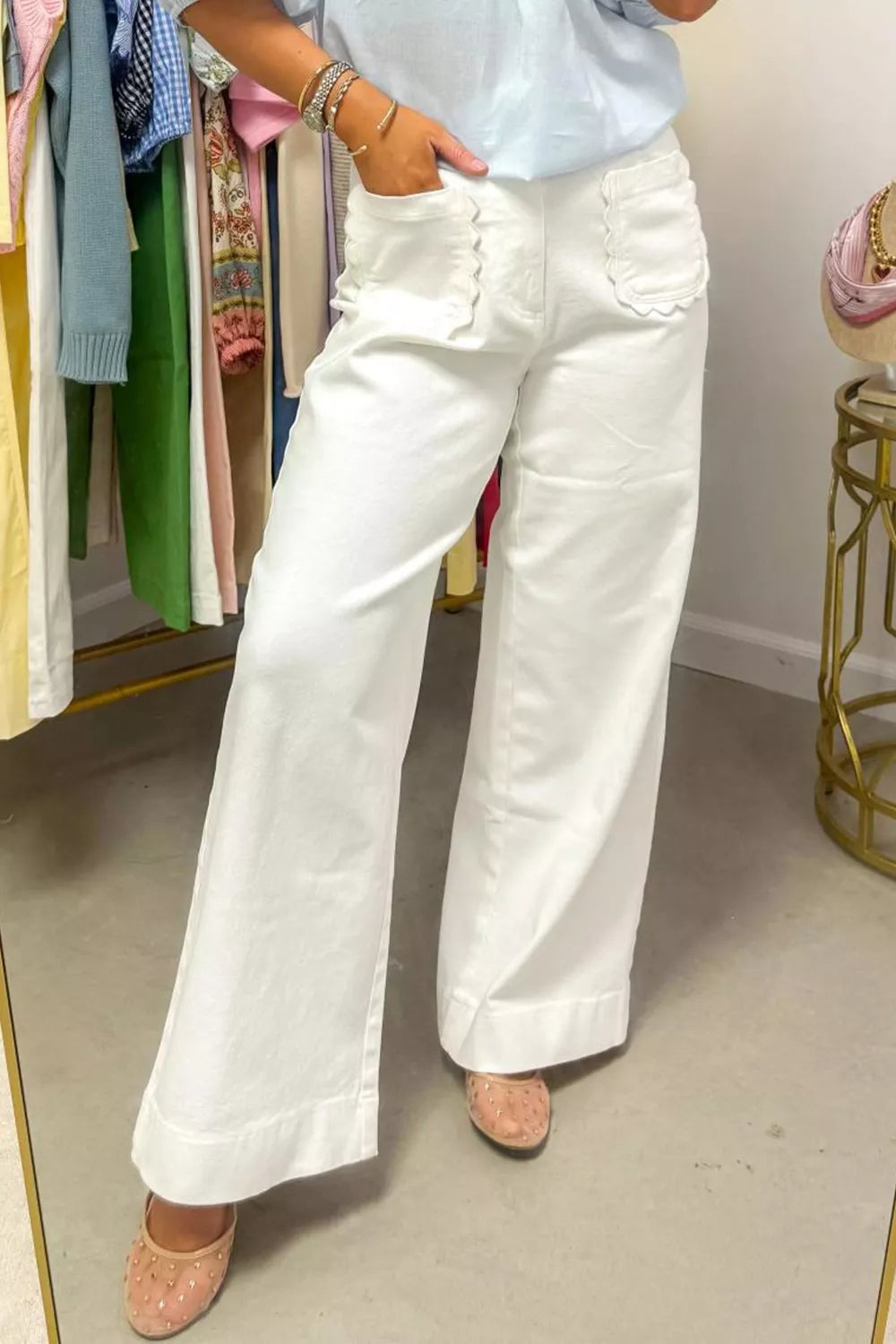 Person wearing white wide-leg jeans in a clothing store.