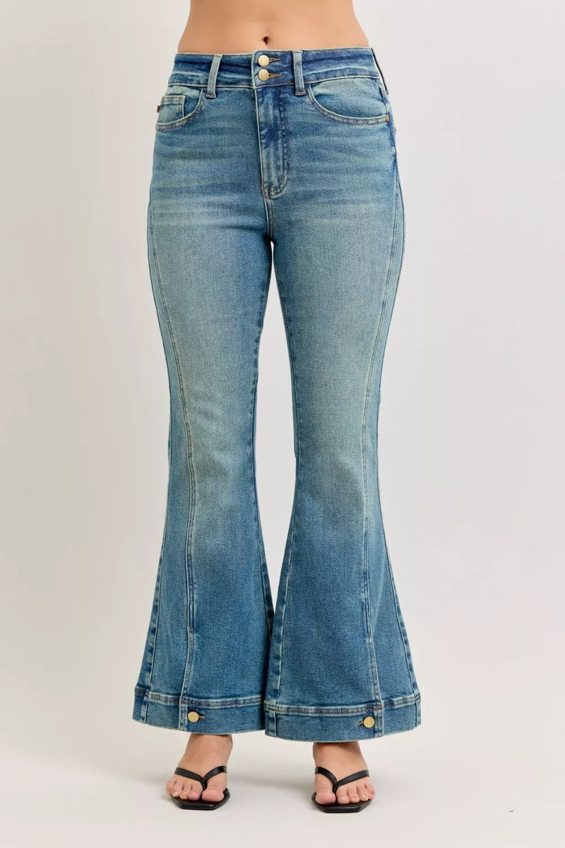 Flared jeans with button details on a plain background
