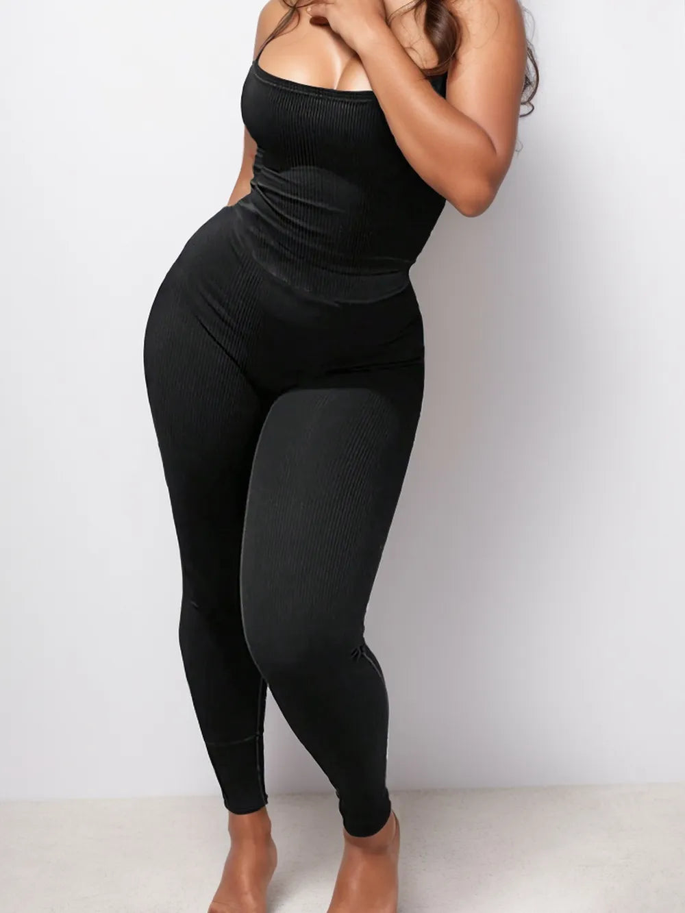 Person wearing a black bodysuit against a white background