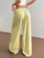 Light green wide-leg pants worn by a person on a wooden floor with a white wall background