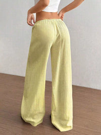 Light green wide-leg pants worn by a person on a wooden floor with a white wall background