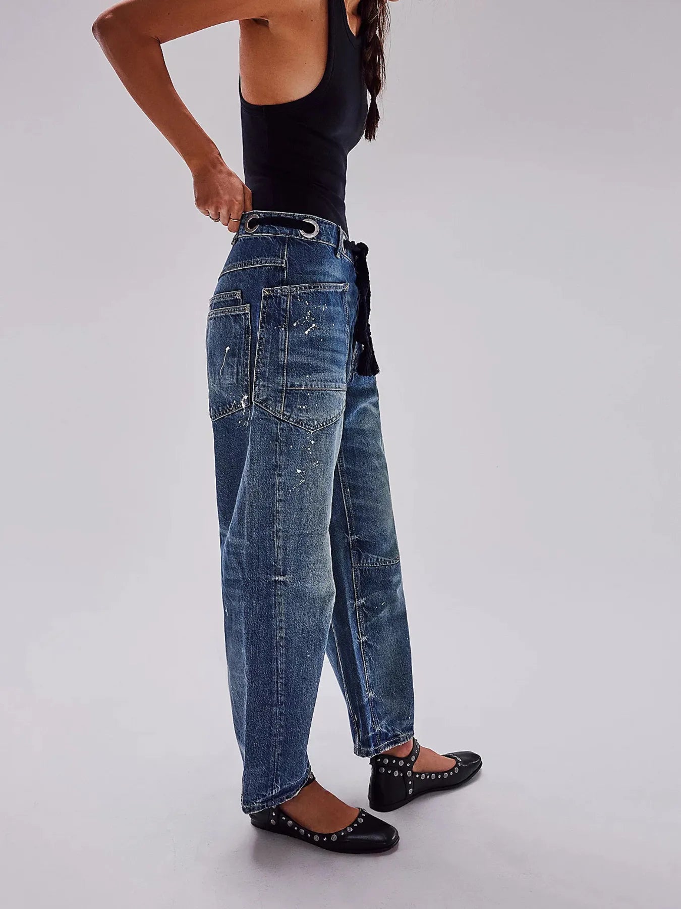 Person wearing blue jeans and black shoes on a plain background