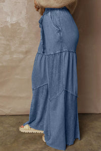 Blue layered dress worn by a person against a beige wall.