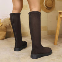 Brown knee-high boots worn by a person, with a neutral background.