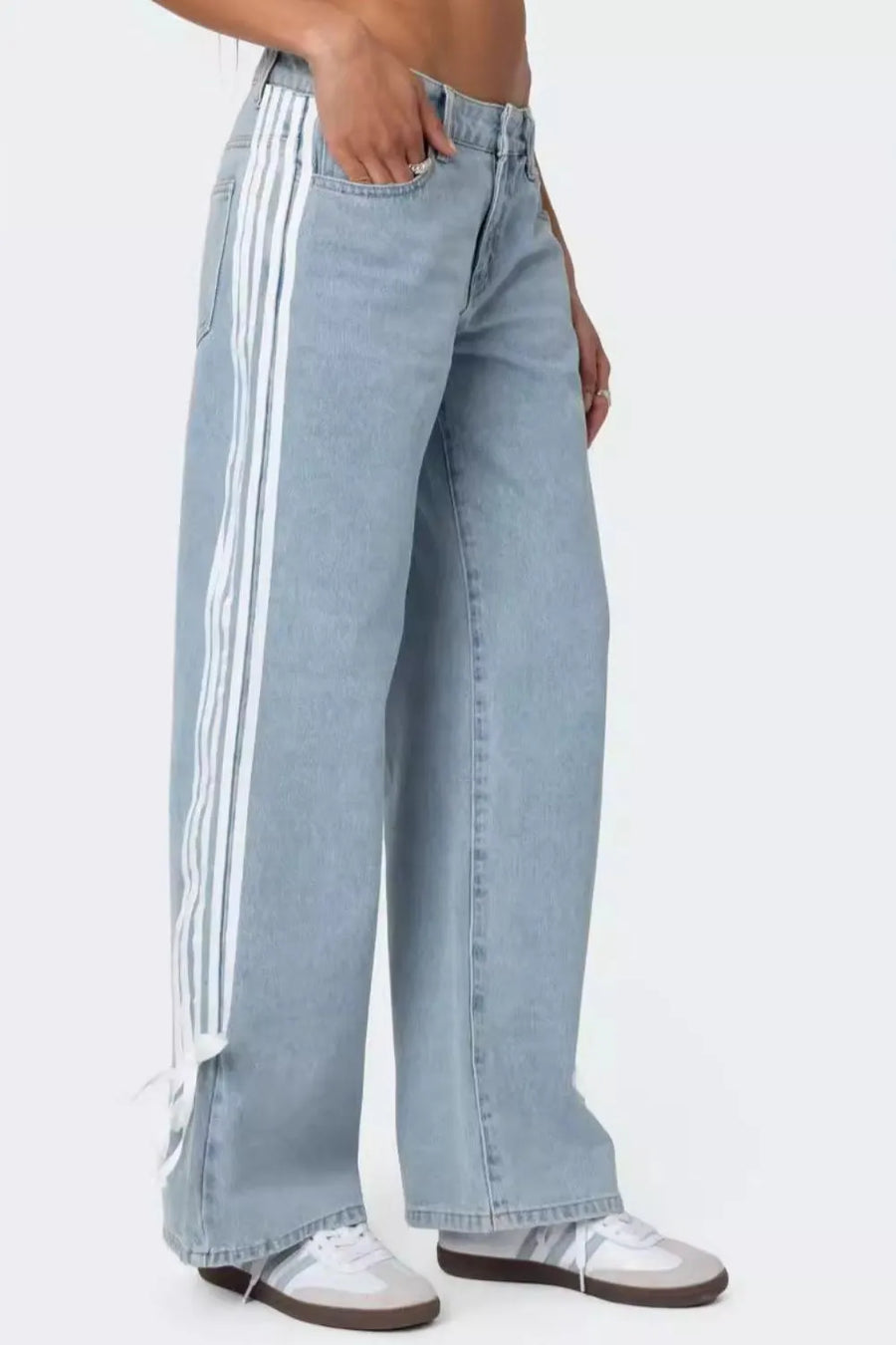 Light blue jeans with white stripes worn by a person on a white background