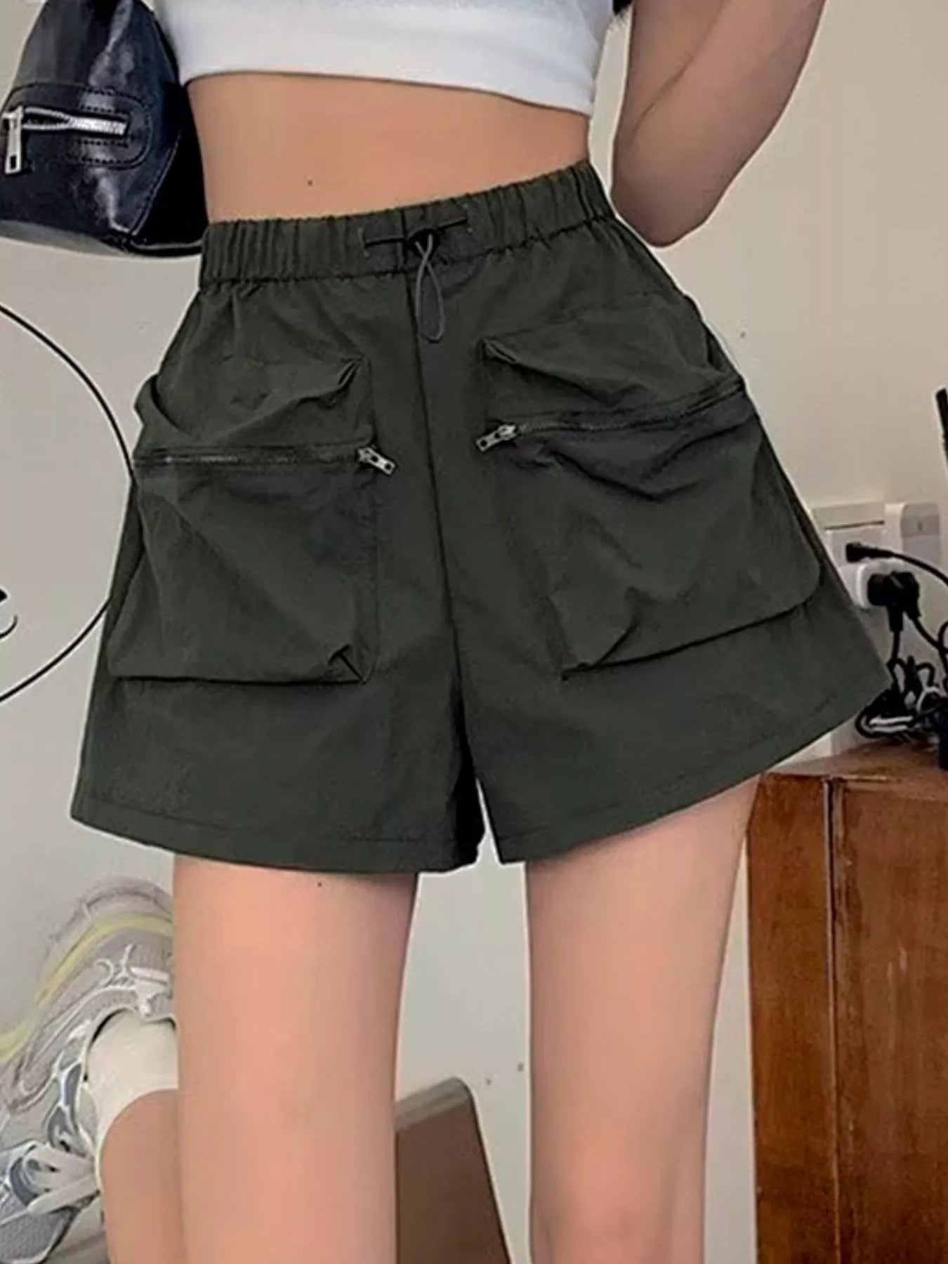 Person wearing dark green cargo shorts with a neutral background