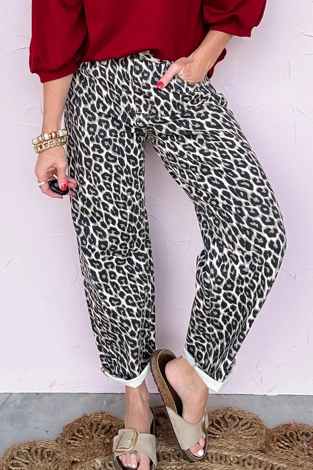 Person wearing leopard print pants with a red top against a white background