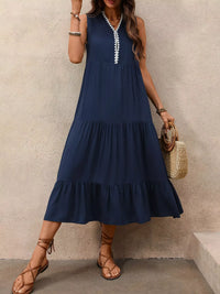 Woman wearing a navy blue dress with white trim, standing against a beige wall.