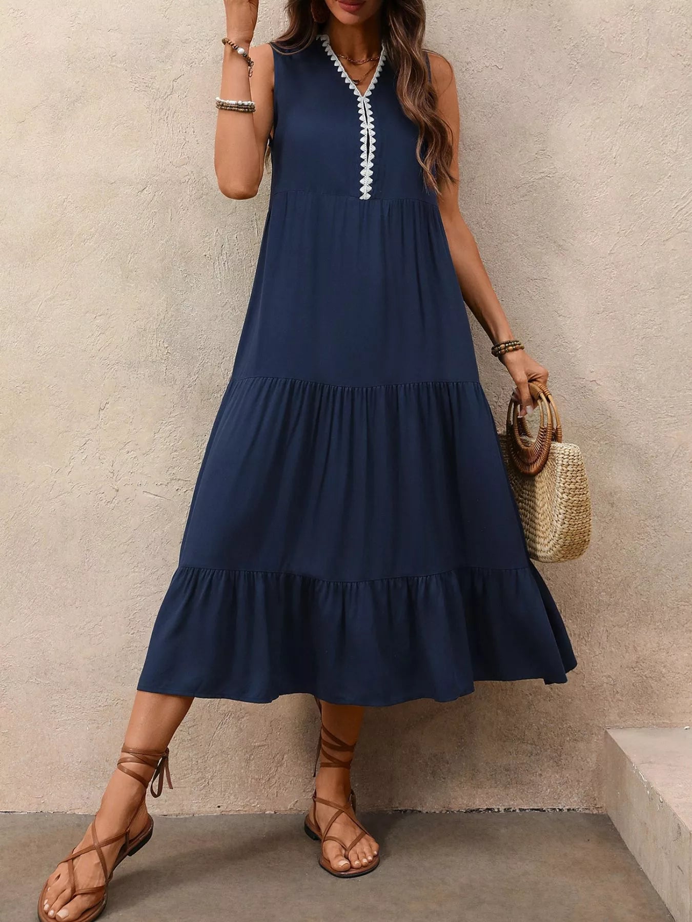 Woman wearing a navy blue dress with white trim, standing against a beige wall.