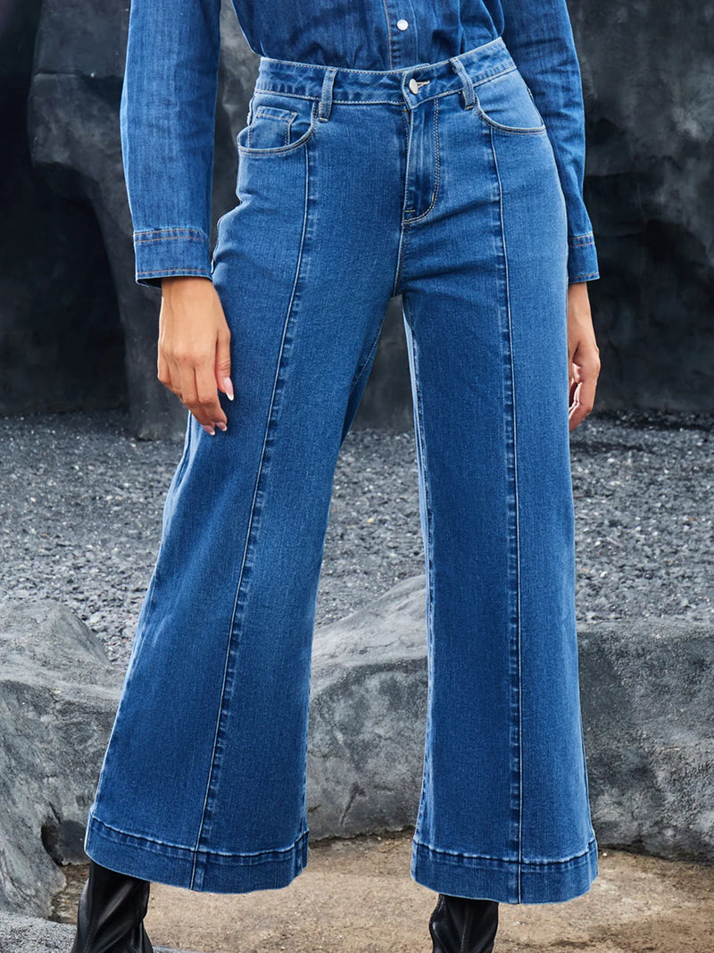 Person wearing blue jeans standing against a rocky background