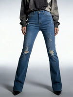 Person wearing blue distressed jeans on a plain background