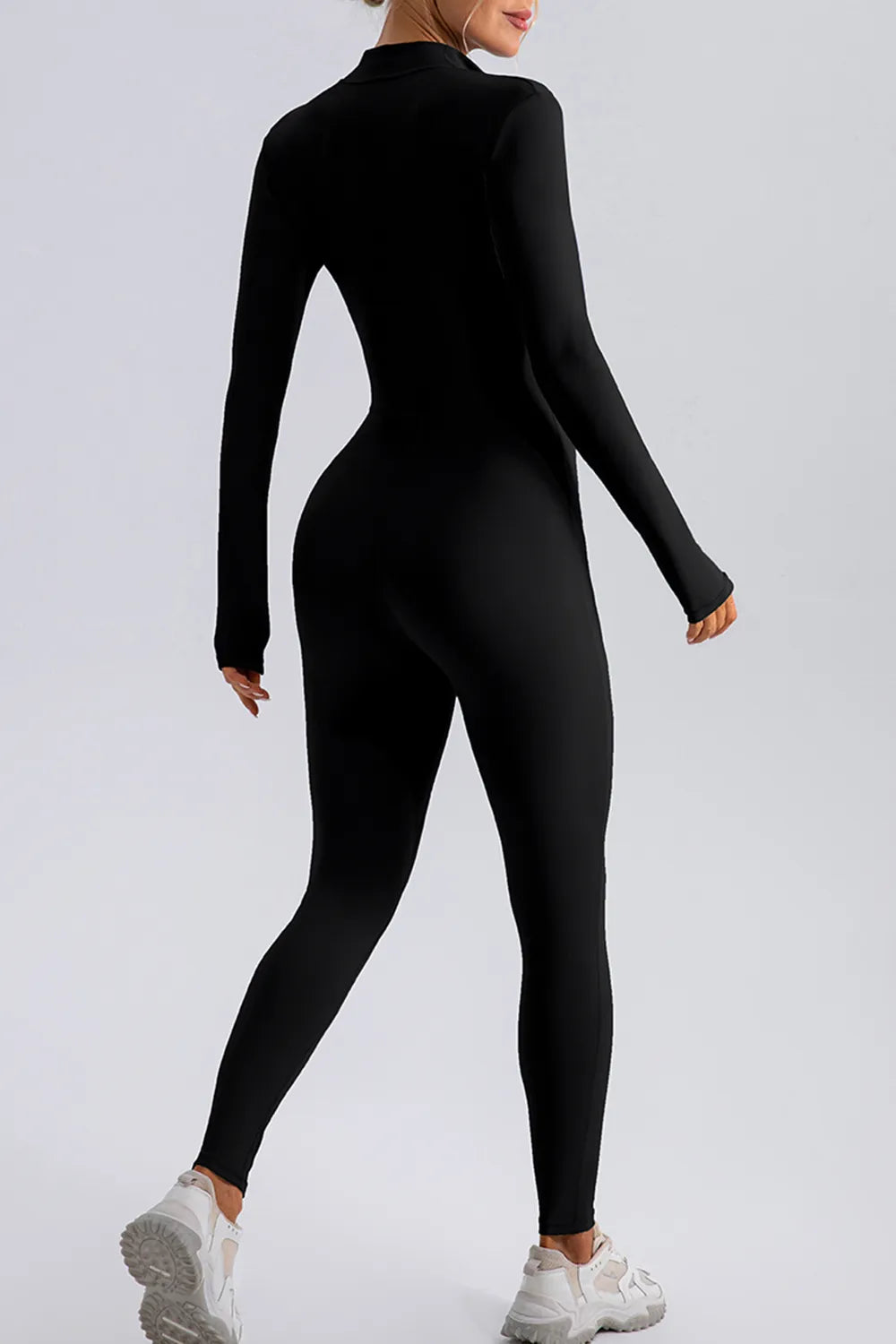 Person wearing a black bodysuit on a light gray background