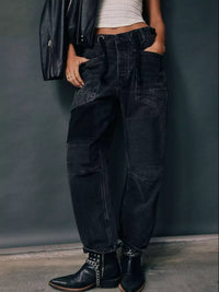 Person wearing black cargo pants and a leather jacket against a dark background