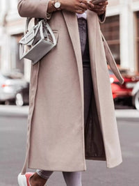 Person wearing a long beige coat on a city street