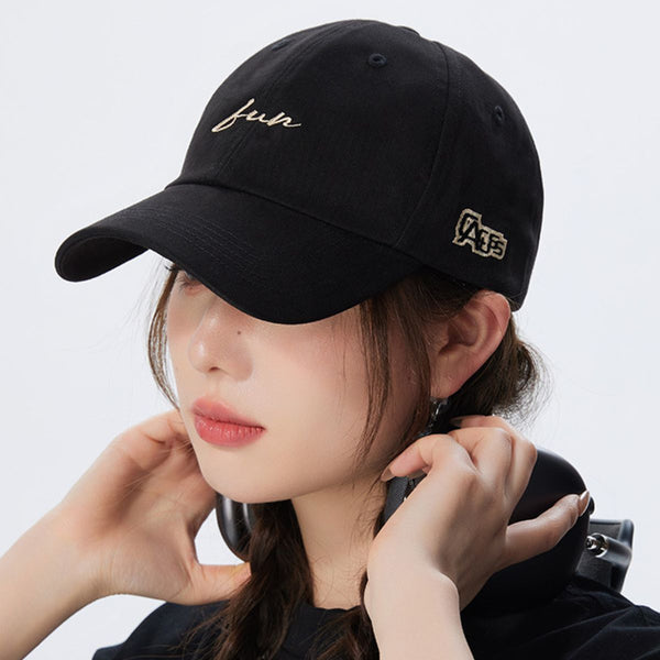 Person wearing a black cap with gold embroidery on a white background
