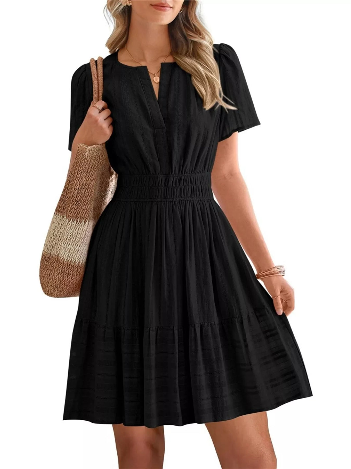 Woman wearing a black dress holding a striped bag on a white background