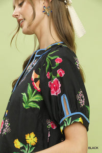 Woman wearing a black top with colorful floral embroidery on a light green background