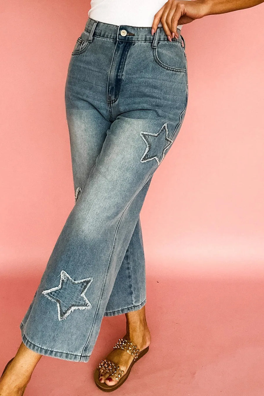 Blue jeans with star patches on a pink background
