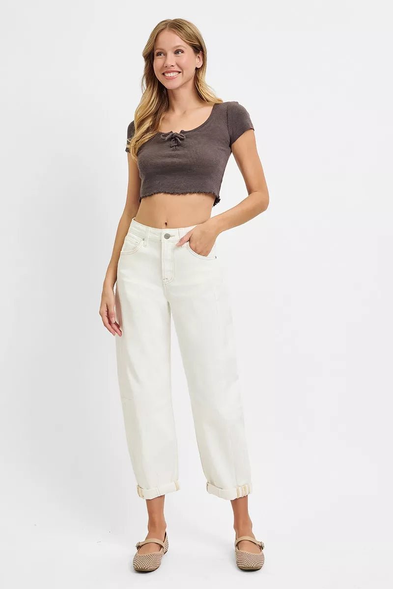 Woman wearing a brown crop top and white pants on a white background