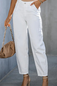Person wearing white pants with a brown handbag against a gray background