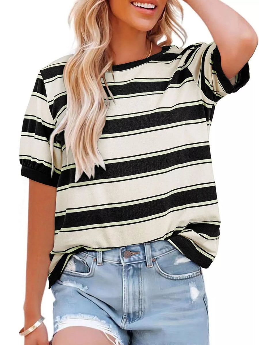Woman wearing a black and white striped shirt with denim shorts on a plain background