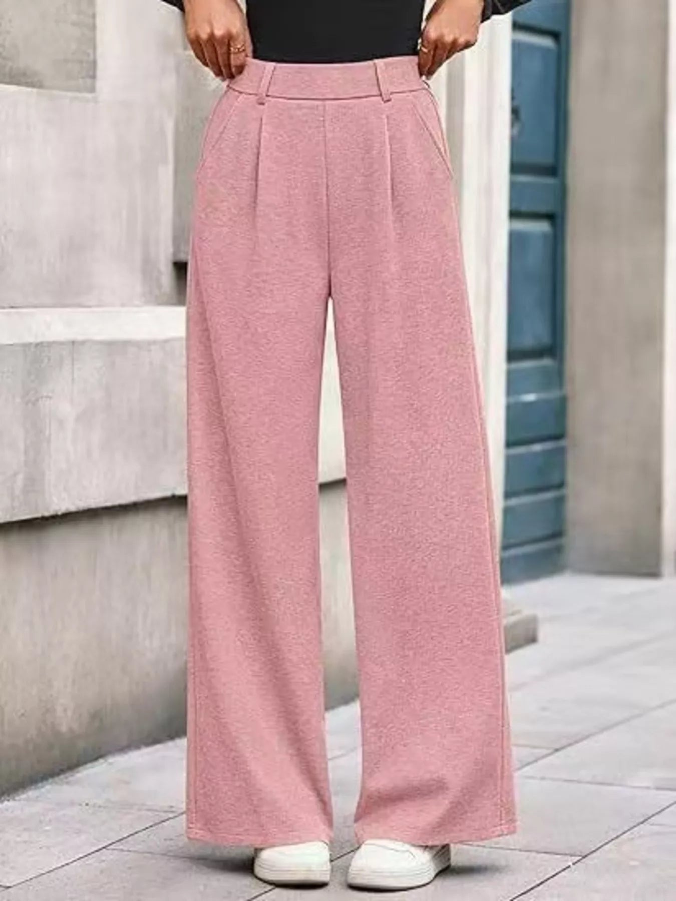Person wearing pink wide-leg pants standing on a stone pavement.