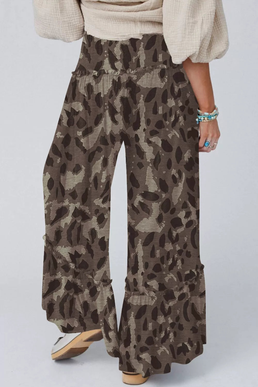 Person wearing leopard print pants on a plain background