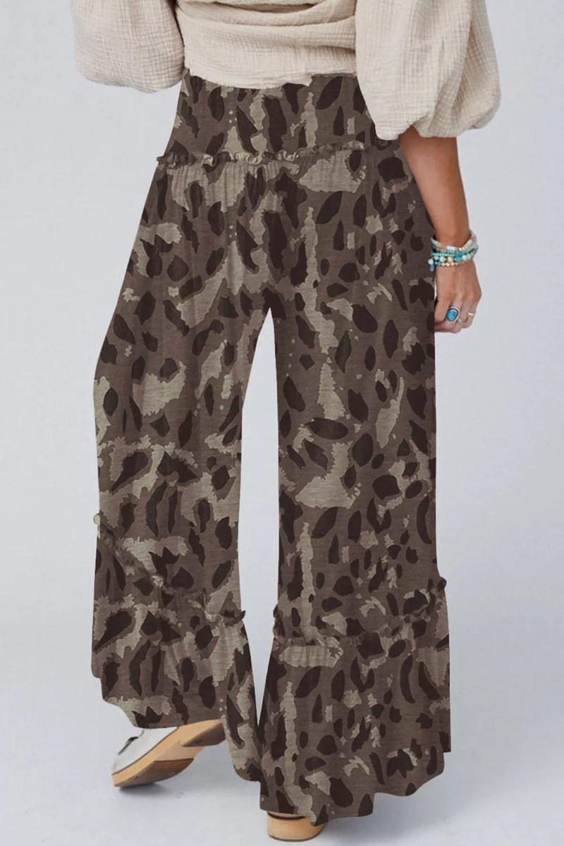 Person wearing leopard print pants on a plain background