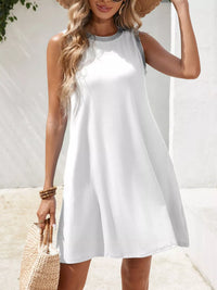 Woman wearing a white sleeveless dress with a straw bag against a white background