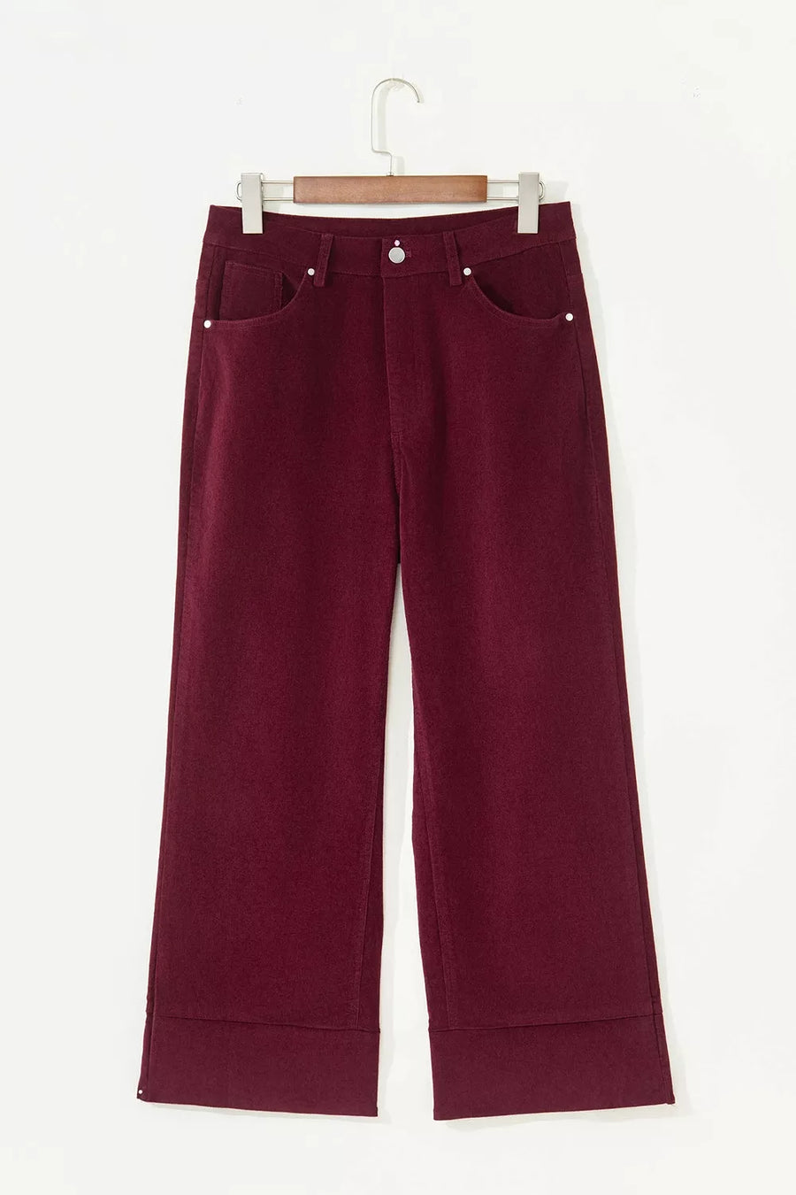 A pair of dark burgundy cropped pants with a wide leg and cuffed hems, hanging on a wooden hanger against a plain white background.