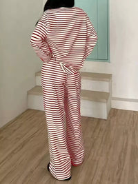 Person wearing a red and white striped outfit standing on a wooden floor.