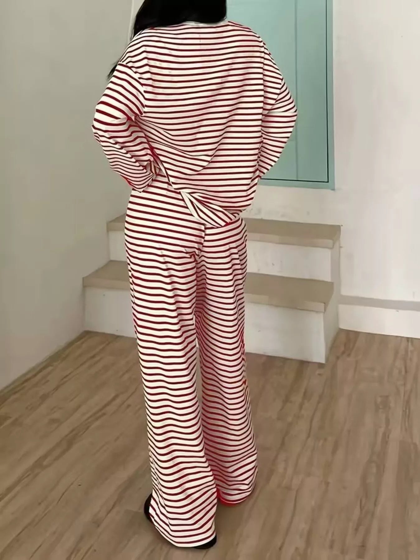 Person wearing a red and white striped outfit standing on a wooden floor.