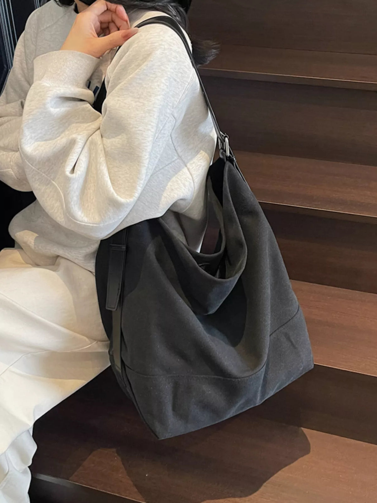 Person holding a gray bag on a wooden floor