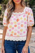 Woman wearing a colorful floral blouse with lace details and blue jeans.