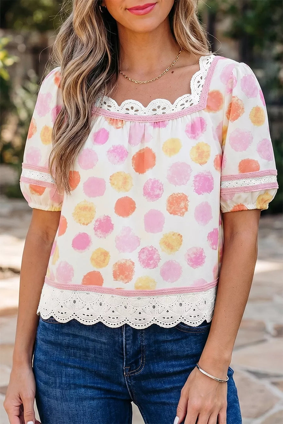 Woman wearing a colorful floral blouse with lace details and blue jeans.