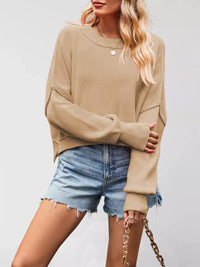 Woman wearing a beige sweater and denim shorts on a plain background