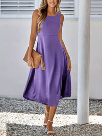 Woman wearing a purple dress holding a brown clutch against a white background