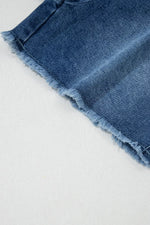 Close-up of a blue denim skirt with frayed hem on a light gray background