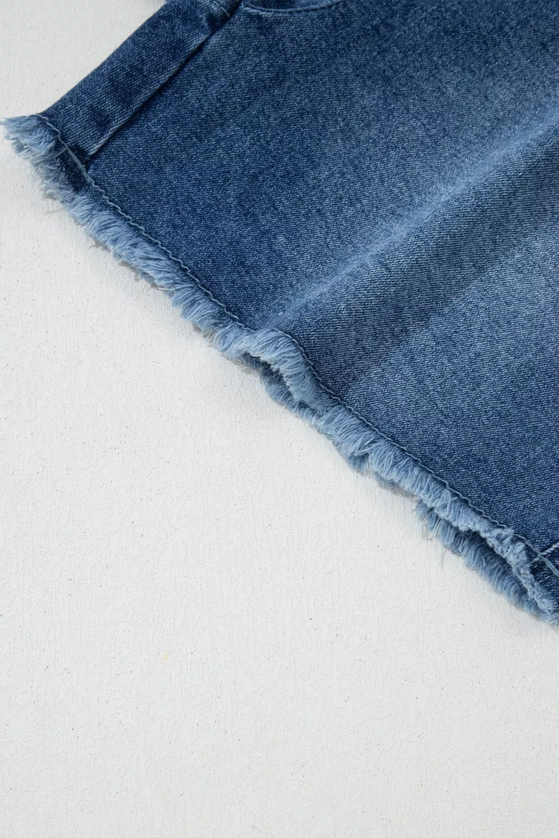 Close-up of a blue denim skirt with frayed hem on a light gray background