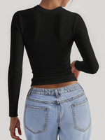 Person wearing a black long-sleeve top and light blue jeans on a white background