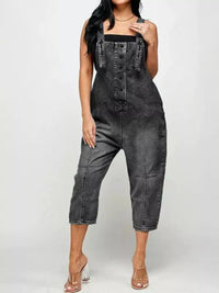 Person wearing a black denim jumpsuit on a white background