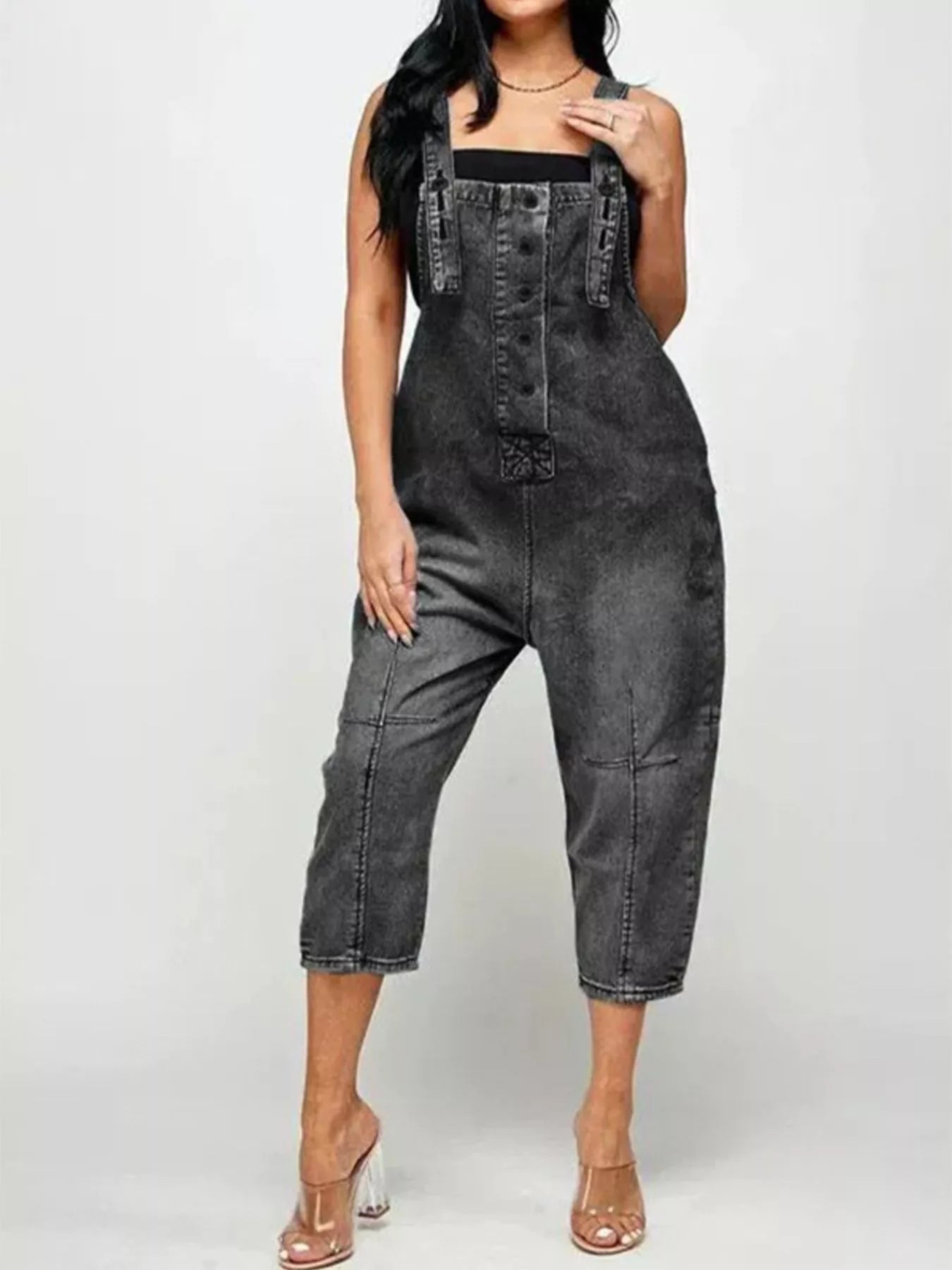 Person wearing a black denim jumpsuit on a white background