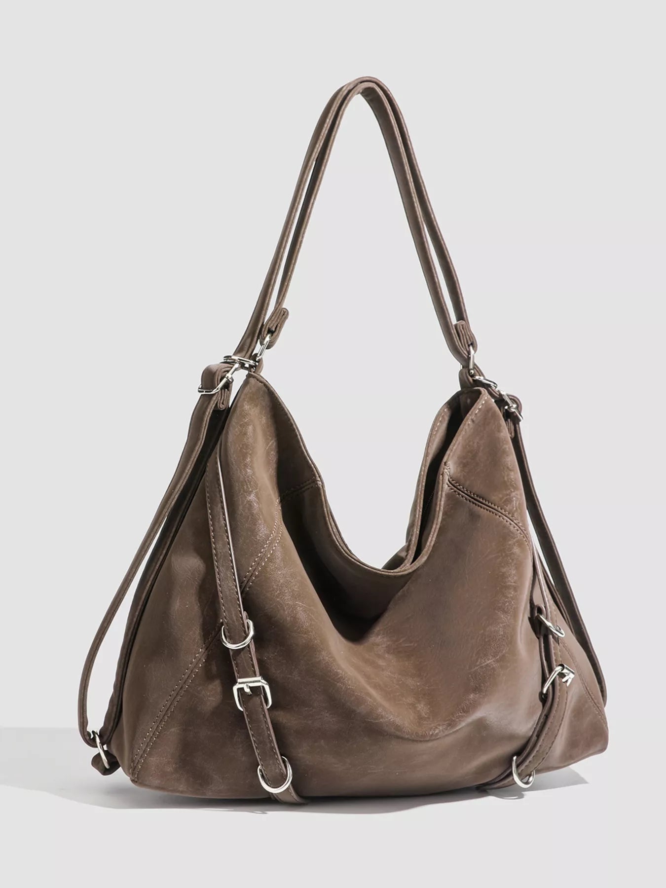 Brown leather handbag with silver buckles on a white background